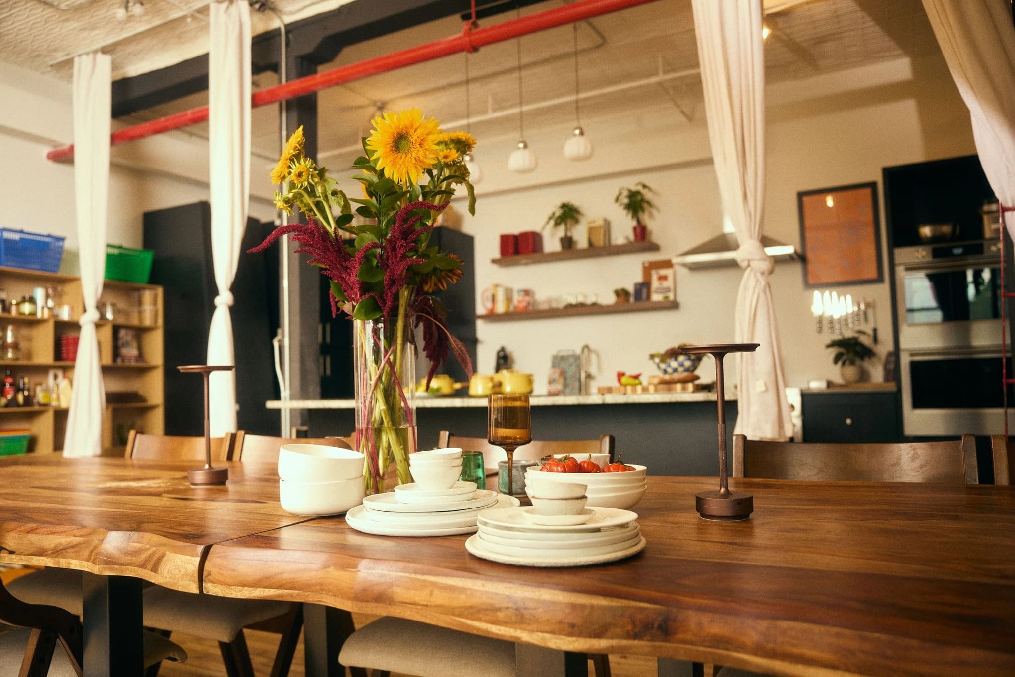 The long wooden dining table set with flowers and tableware, looking toward the kitchen