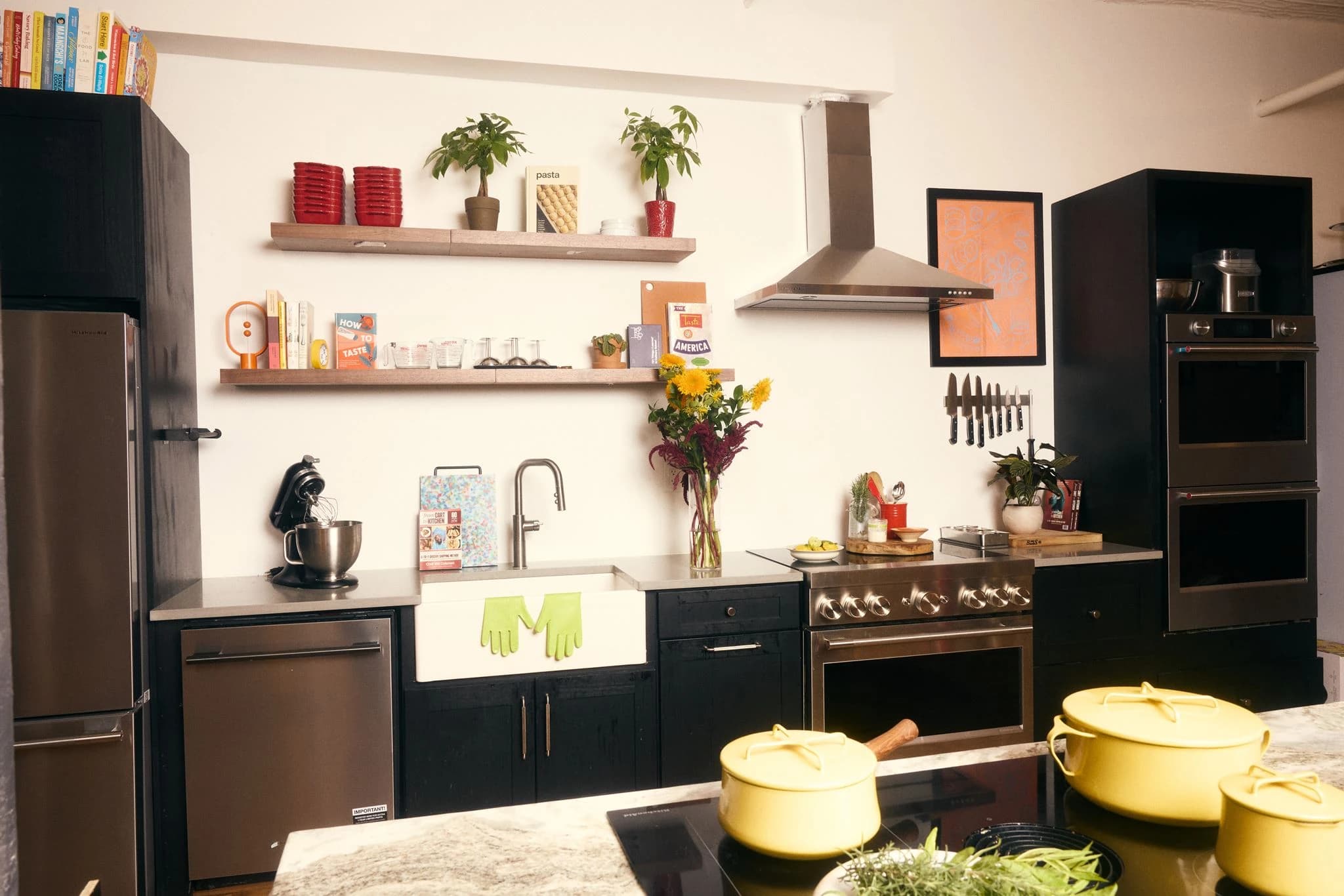 The production kitchen with a farmhouse sink, range, double ovens, and yellow cookware on the prep island