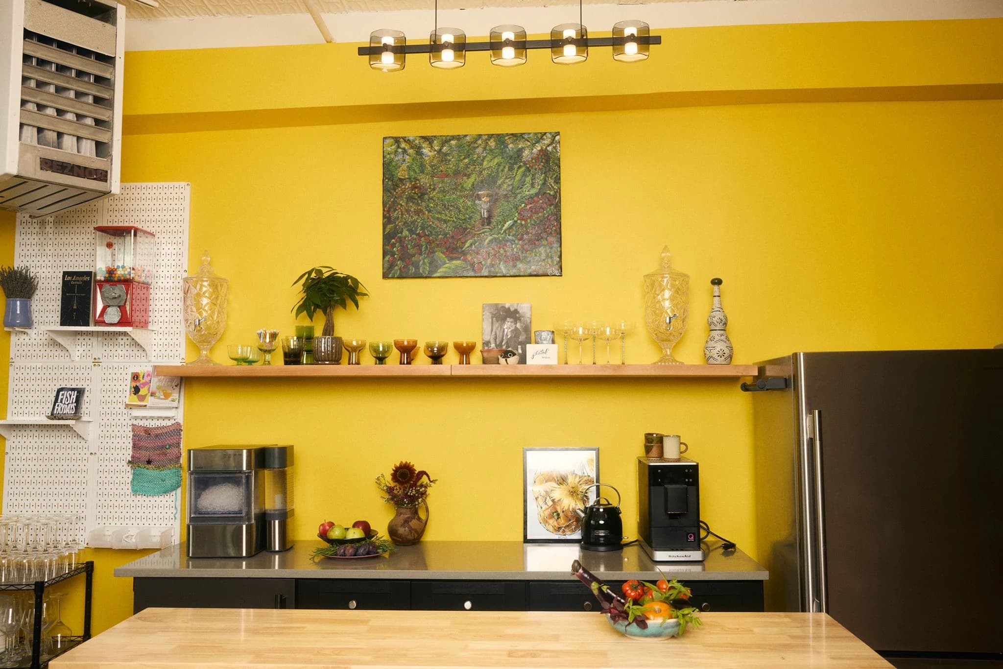 The yellow hosting bar with glassware, open shelving, and a wooden worktop